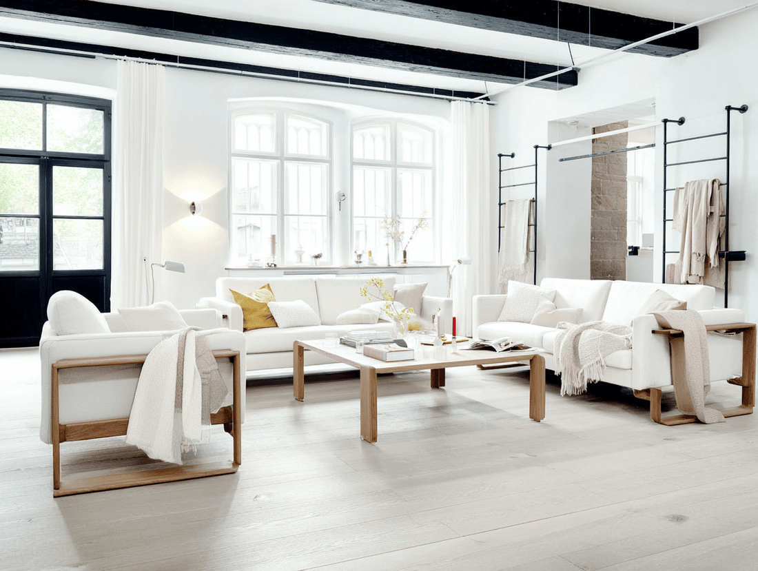 Bright Scandinavian living room with white sofas, wooden furniture, and large windows