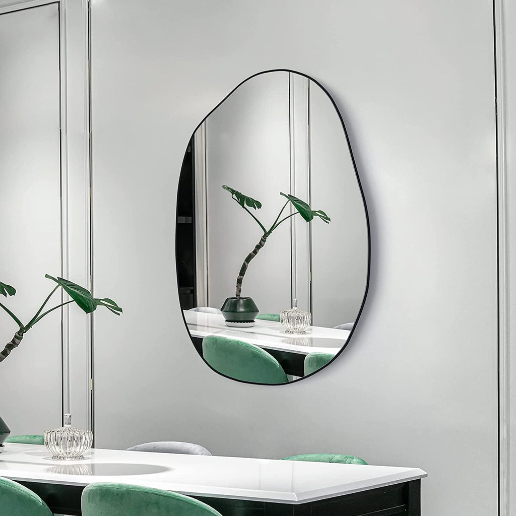 Modern irregular oval wall mirror with black frame for dining room or living space decor.
