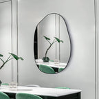 Modern irregular oval wall mirror with black frame for dining room or living space decor.
