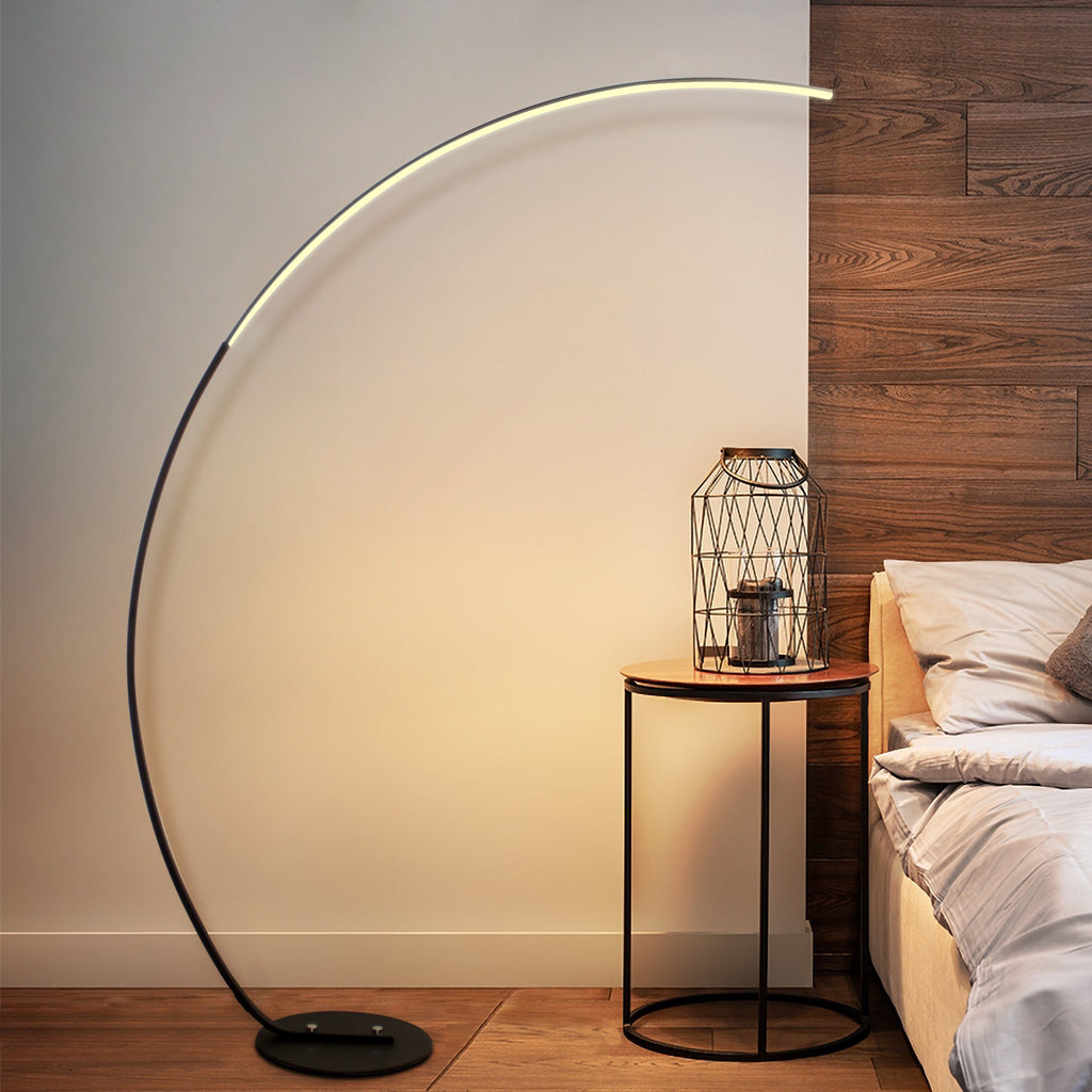 Stylish curved floor lamp beside bed and side table