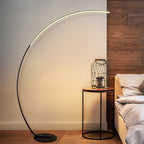 Stylish curved floor lamp beside bed and side table
