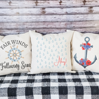 Coastal nautical throw pillows with anchor and ship wheel designs for beach house decor.
