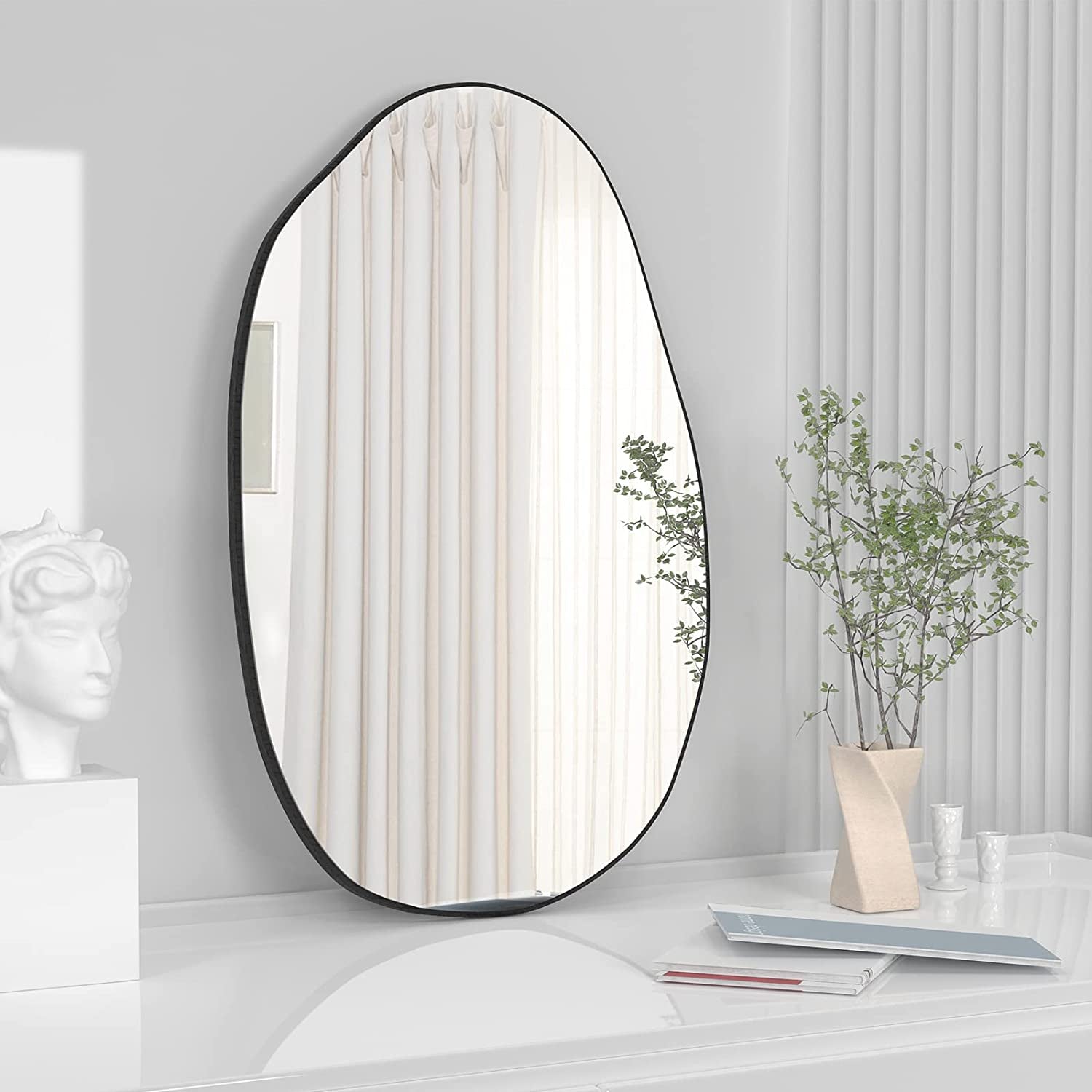 Irregular oval wall mirror with black frame for modern bedroom, bathroom, or hallway decor.
