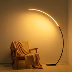 Modern arc floor lamp with warm LED lighting beside chair