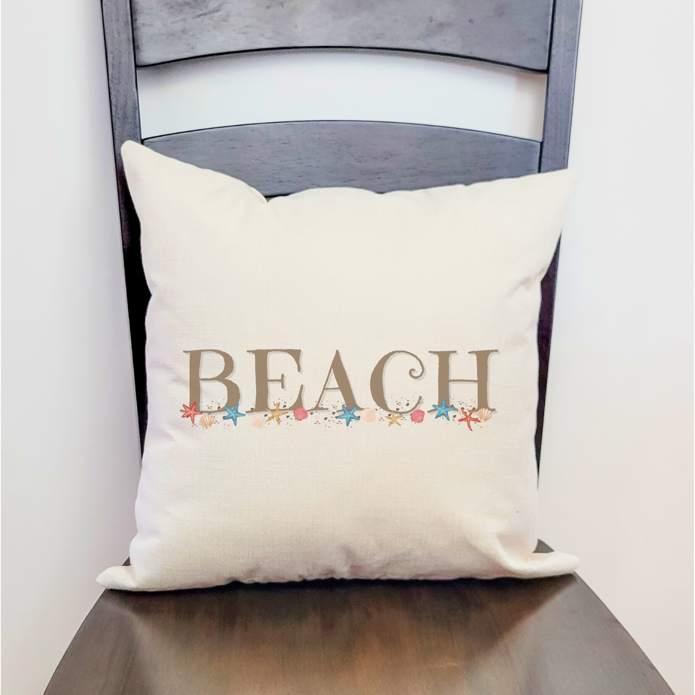 Coastal pillow cover with “BEACH” design and seashell accents for nautical home decor.
