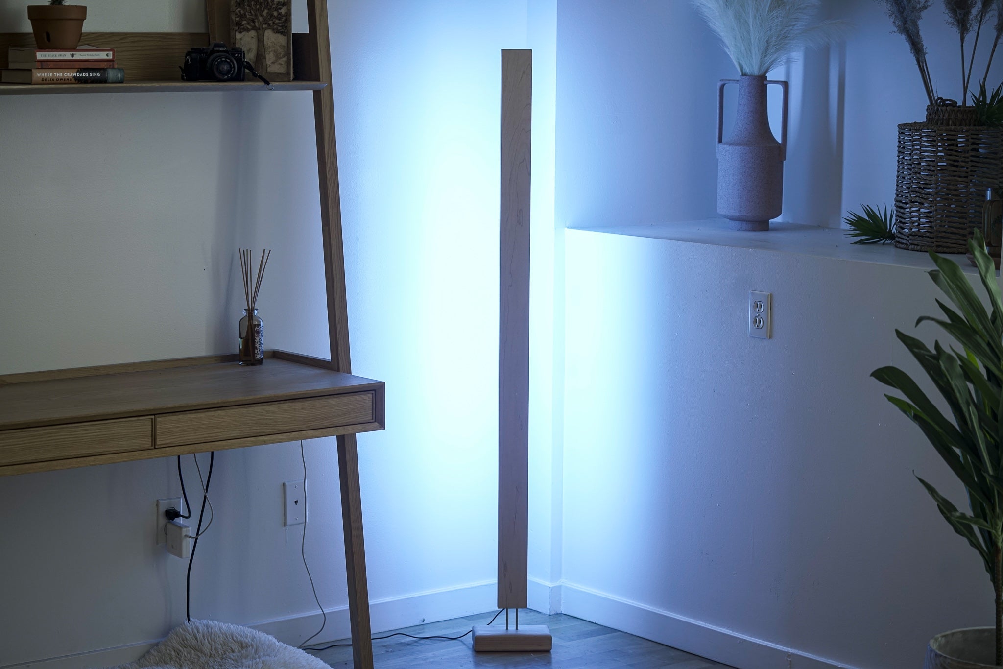 Wooden LED corner floor lamp with cool white ambient lighting for modern spaces.
