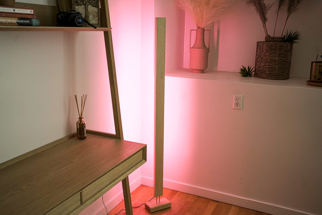 Wooden LED corner floor lamp with soft pink ambient lighting for modern homes.
