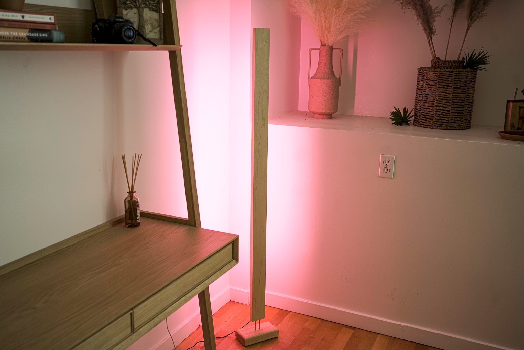Wooden LED corner floor lamp with soft pink ambient lighting for modern homes.
