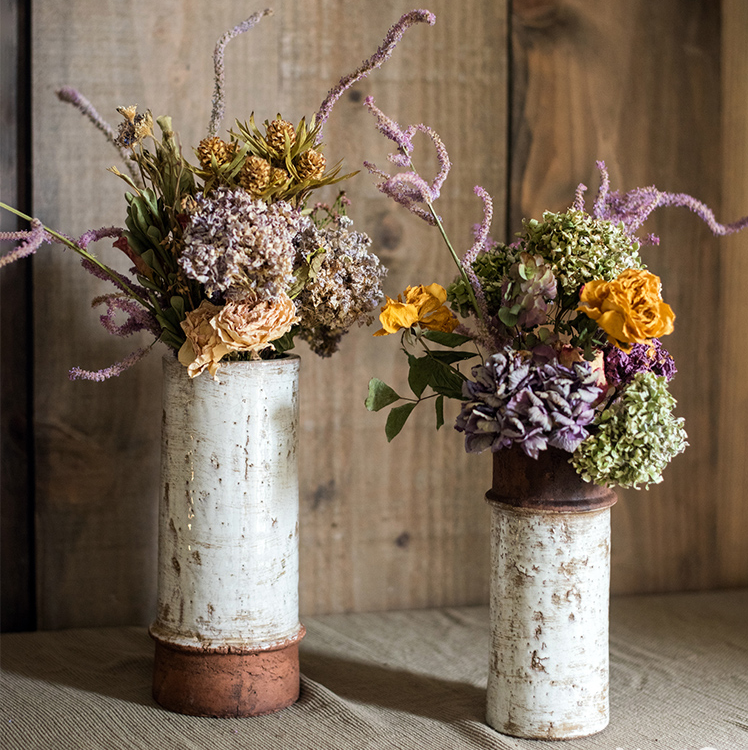 Tall rustic ceramic vases with dried floral arrangements for vintage farmhouse decor.
