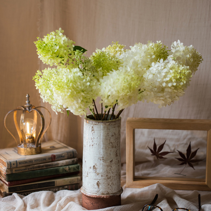 Rustic tall ceramic vase with white and green hydrangeas for farmhouse home decor.
