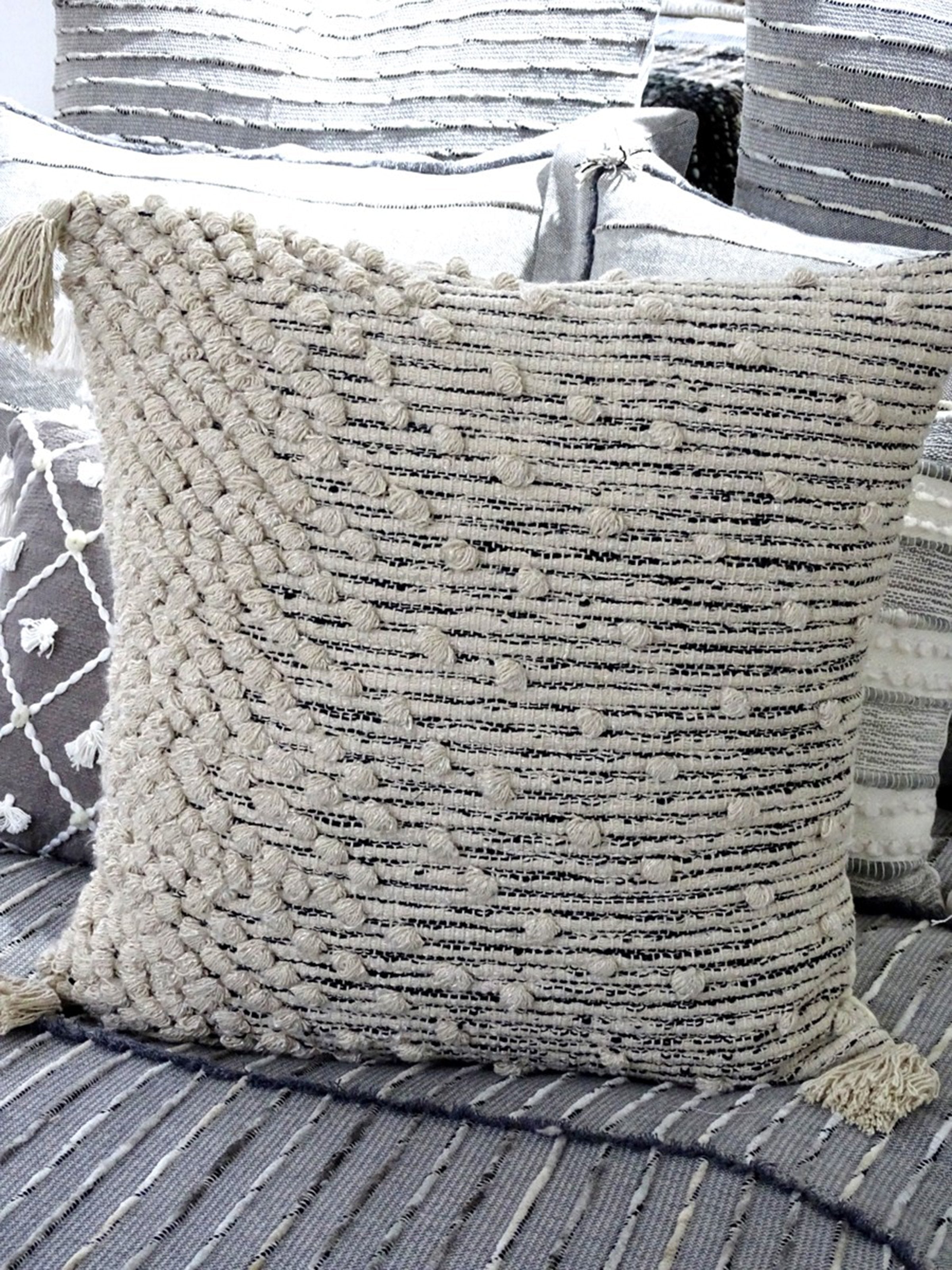 Boho textured throw pillow with woven design and tassels for cozy home decor.
