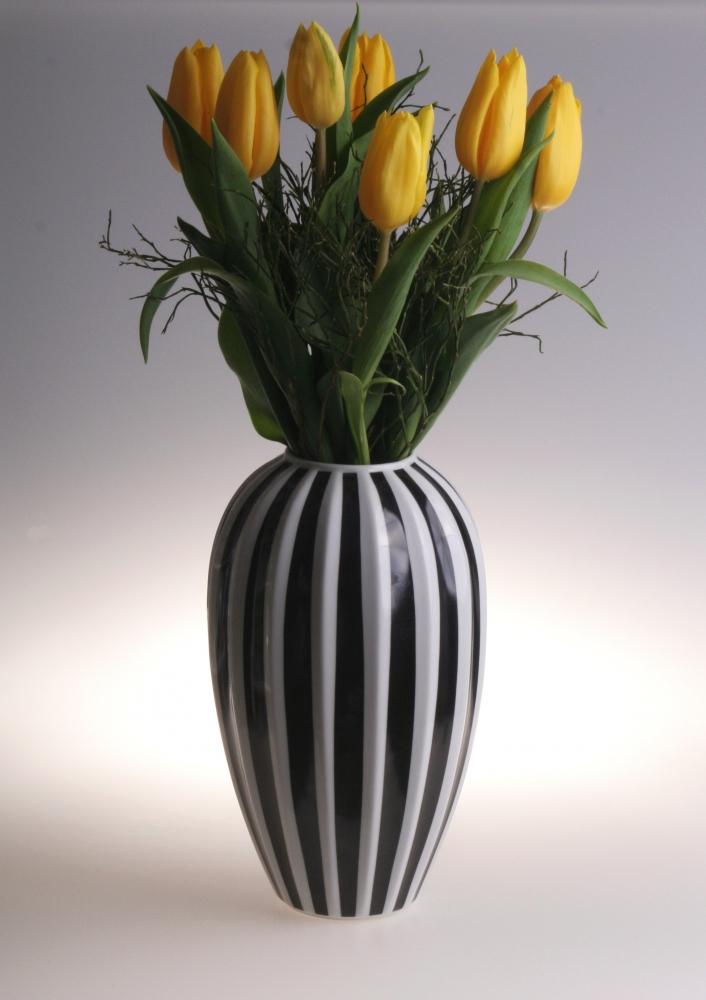 Modern black and white striped ceramic vase with yellow tulips for stylish decor.
