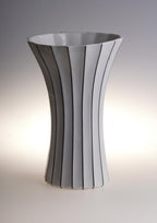 Stylish black and white striped ceramic vase with flared modern design.
