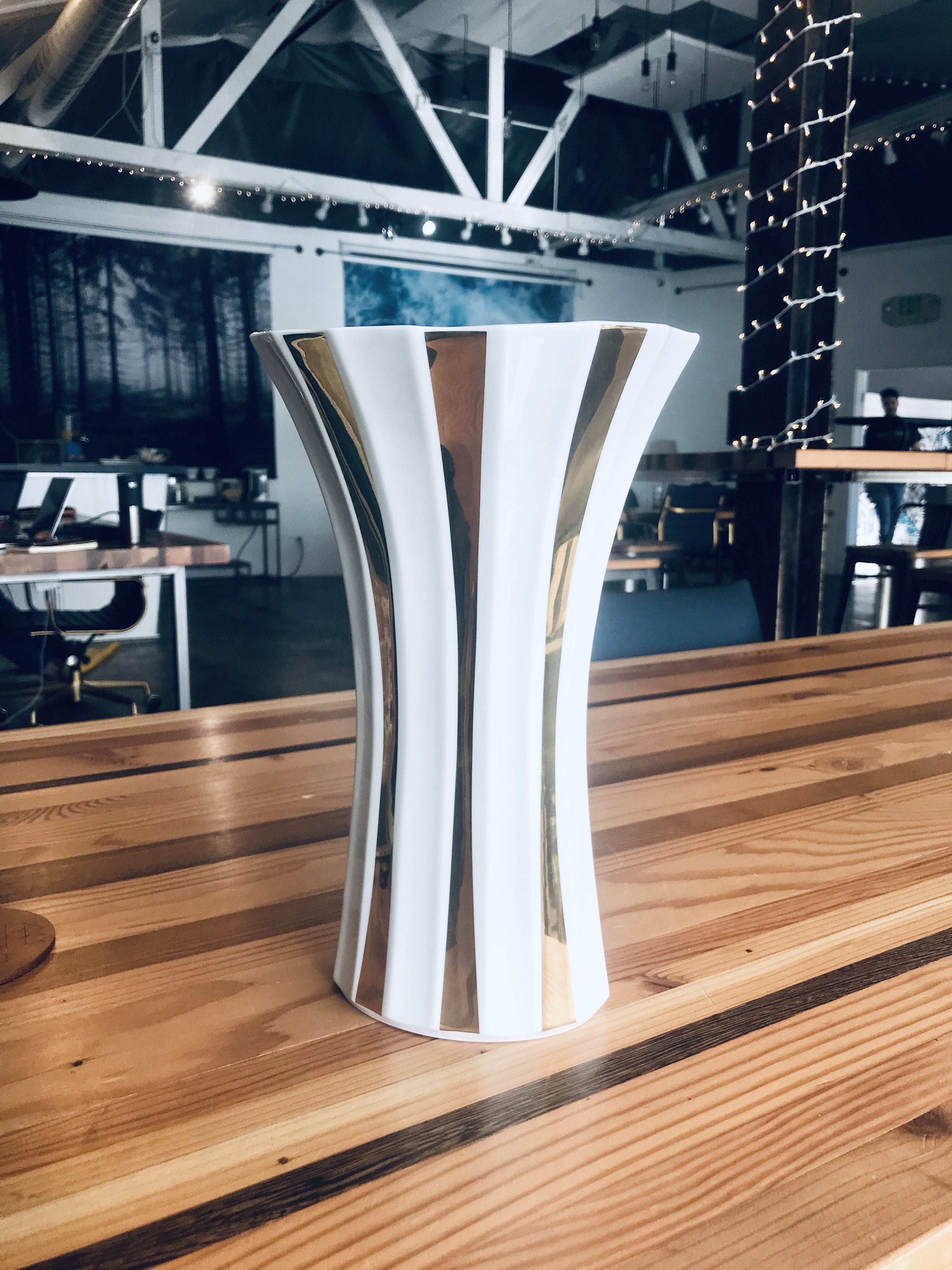 Modern white and gold striped ceramic vase with flared design for elegant home decor.
