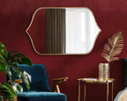 Decorative gold-framed wall mirror with unique curved design for living room or entryway.

