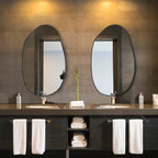 Set of two irregular oval wall mirrors with black frames for modern bathroom vanity decor.
