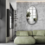 Modern oval wall mirror with black frame, perfect for living room or hallway decor.
