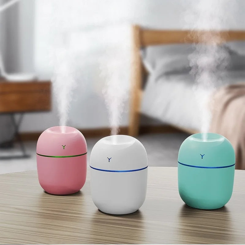 Small portable humidifiers in pink, white, and green releasing mist