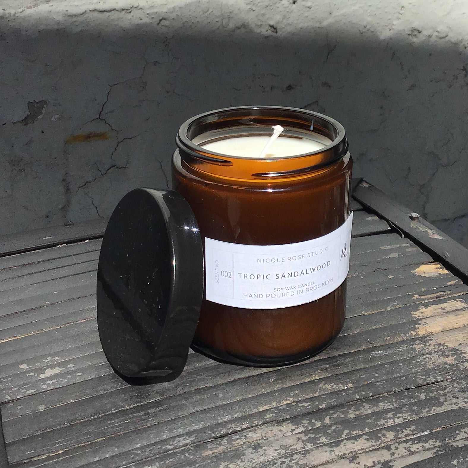 Honeysuckle soy candle in amber glass jar with lid, natural floral aroma.
