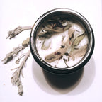 Herbal soy candle with dried lavender and sage leaves for natural aromatherapy.
