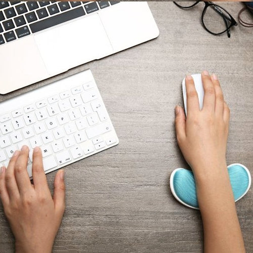 Person using laptop with mouse and blue ergonomic wrist rest pad