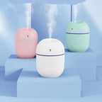 Portable mini humidifiers in pink, white, and green releasing mist