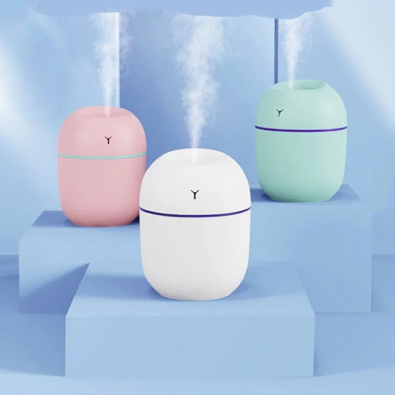 Portable mini humidifiers in pink, white, and green releasing mist