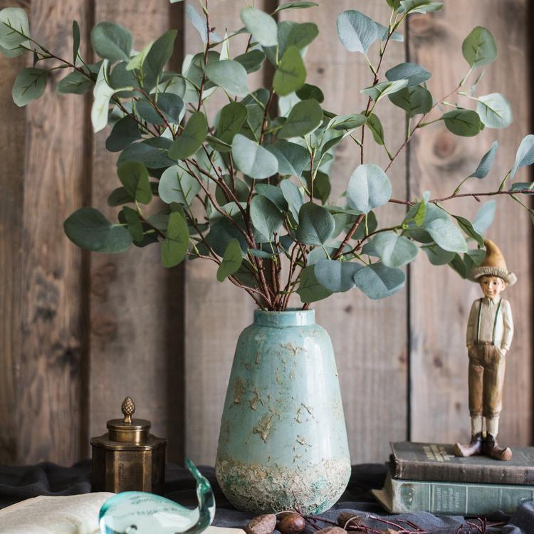 Vintage green ceramic vase with eucalyptus branches for rustic farmhouse home decor.
