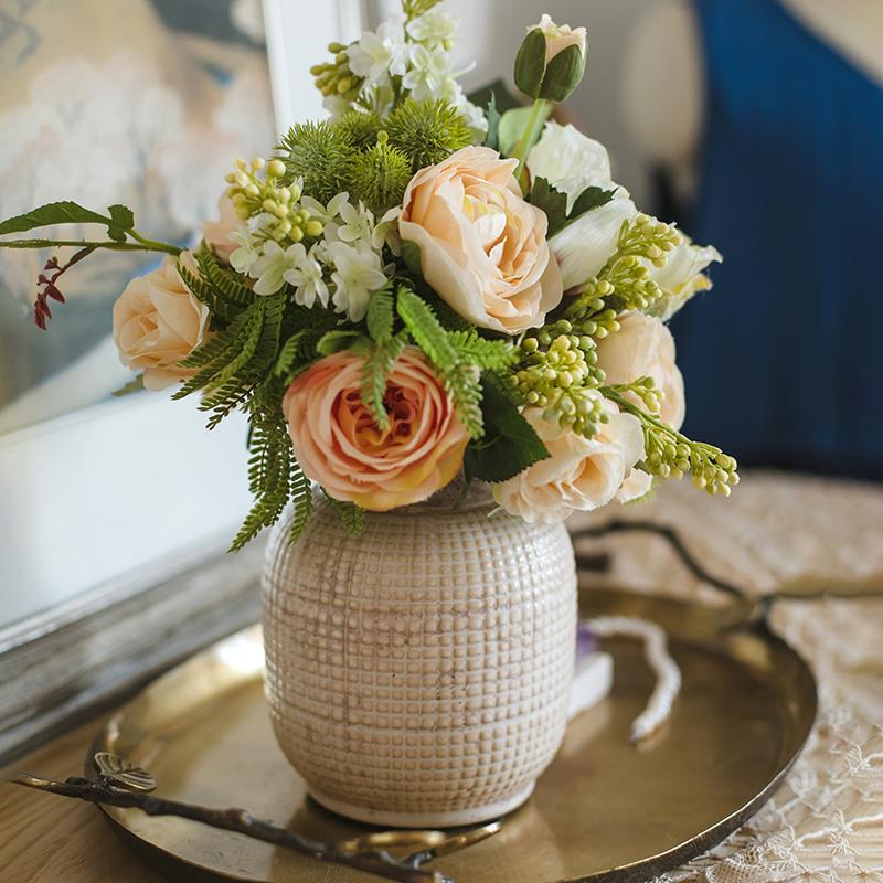 Elegant ceramic vase with peach roses and greenery for table centerpiece decor.
